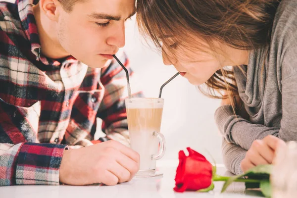 Ostříhaná žena a muž v lásce pít latté se stébly ze stejné sklenice, trávit volný čas spolu. — Stock fotografie