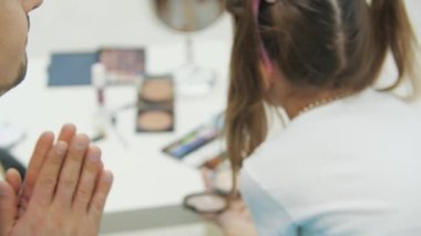 Babasına makyaj yapan küçük bir çocuğun yakın çekimi. Babam aptal bir ifadeyle bakıyor..