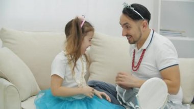 Kasklı ve kolyeli komik bir baba kızını gıdıklıyor..
