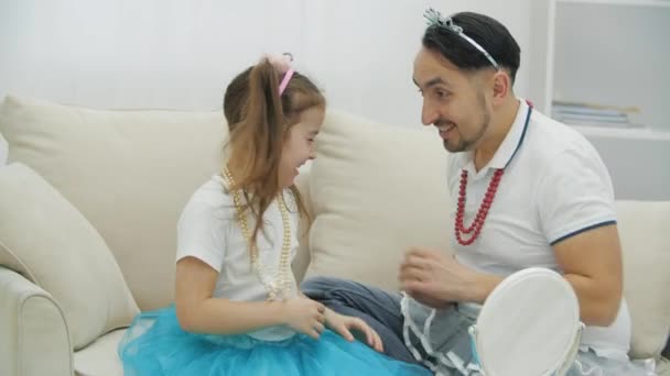 Funny father in headgear and necklace tickling his little daughter. — Stock Video