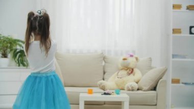 Küçük peri elinde sihirli değnekle kanepede oyuncak ayısını büyülüyor, sonra kameraya dönüyor, önünde asasını sallıyor, gülümsüyor..