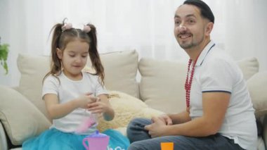 Komik baba-kız, prenseslerle oynuyorlar, kanepede oturuyorlar, başlık takıyorlar..