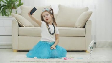 Taç takan, elbise takan, kolye takan ve selfie çeken güzel bir çocuk..