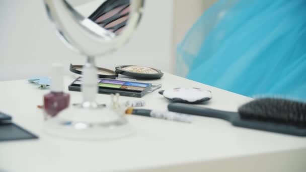 Camera beweegt langs de tafel vol met cosmetische benodigdheden, richt zich dan op het schattige kind dat make-up doet voor haar vader. — Stockvideo