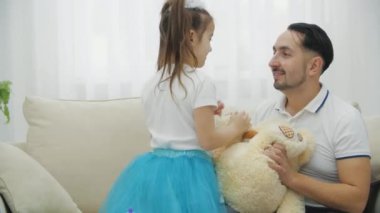 Güzel tacın içindeki neşeli kız babasının yanaklarını çekiyor.