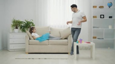 Küçük peri ve baba oynuyor, kız sihirli değnek sallıyor, ve baba balerin eteği ve kolye giyiyor, aptal gibi görünüyor..