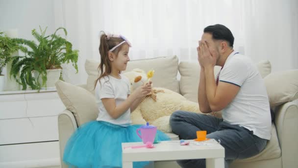 Grappige papa en dochter spelen in prinsessen, zitten op de bank, dragen hoofddeksels. — Stockvideo
