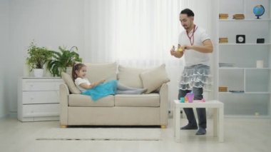 Küçük peri ve baba oynuyor, kız sihirli değnek sallıyor, ve baba onun emirlerine uyuyor, başlık takıyor, ona oyuncak ayı getiriyor, aptal gibi görünüyor..