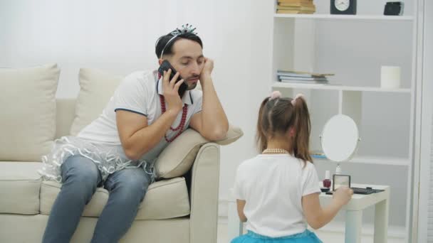 Hezký mladík mluví po telefonu. Jeho dcera je připravena udělat make-up pro svého otce. Šťastný Den otců. — Stock video