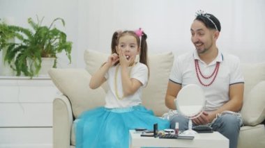 Küçük kız kozmetik fırçasıyla numaralar yapıyor. Baba onun tarafında, Croen ve kolye içinde oturuyor, tereddüt ediyor..