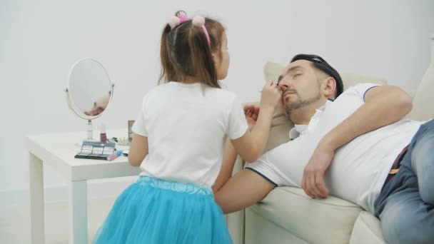 可爱的小孩正在给她爸爸化妆，在他睡觉的时候给他的眼睑蒙上眼影. — 图库视频影像