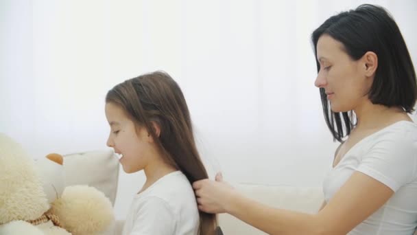 Gros plan vidéo de la jeune mère peigner ses filles cheveux alors qu'elle joue avec l'ours en peluche. — Video