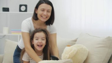 Komik anne etrafta oynaşıyor, kızının saçını bozuyor, rüzgarlı saçlar yapıyor. Umutsuzca gülüyorlar..