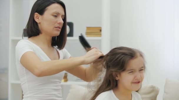 Girls hair is tousled. Mother is trying to comb it, but daughter is freaking. — Stock Video