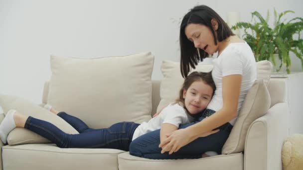 Liten vacker flicka ligger på mammas ben. Mor kör sina fingrar över döttrar kropp. — Stockvideo