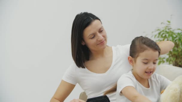 4k video av omtänksam mor gör hår av sin dotter med nalle i händerna. — Stockvideo