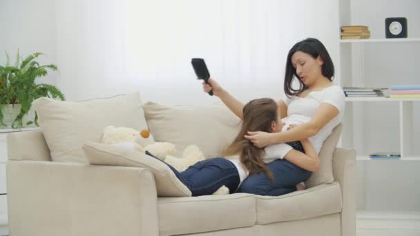 4k vídeo de mãe feliz escovando o cabelo filhas na sala de estar . — Vídeo de Stock