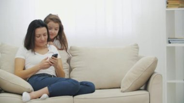 4k video 'da küçük kız annesiyle eğleniyor. Mobil ekrana bakıp gülüyor..