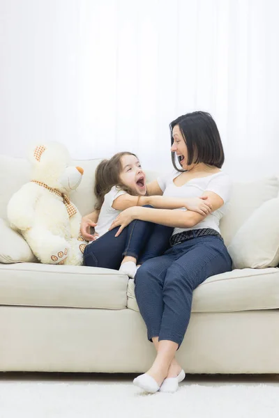 Feliz sonriente madre e hija abrazándose en el sofá. — Foto de Stock