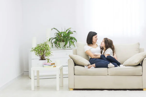 Foto de una hermosa madre abrazándose con su linda hijita y mirándose en la sala de estar. — Foto de Stock