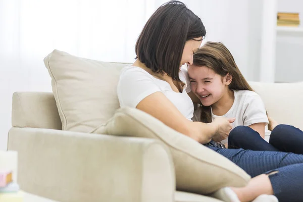 Foto de madre feliz y su hija hablando en el sofá en la sala de estar. — Foto de Stock