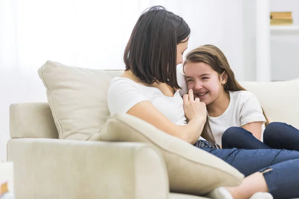 Foto de madre feliz y su hija hablando en el sofá en la sala de estar. — Foto de Stock