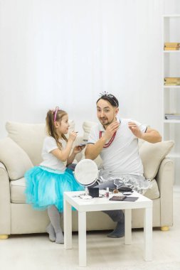 Küçük kız ve baba eğleniyor, prenses kostümü giyiyorlar, baba makyajı yapıyorlar..