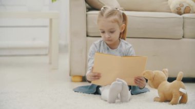 Anaokulu kızının kitap tutuşu ve okumasının 4k yavaş videosu.
