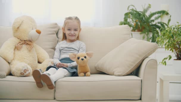 4k slow motion video de la niña linda sentada en un sofá blanco. — Vídeos de Stock