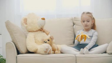 4K yavaş çekim videosu. Sarı saçlı, muz yiyen bir kız..