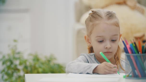4k slowmotion video van schattig kind meisje leren schrijven aan huis tafel. — Stockvideo