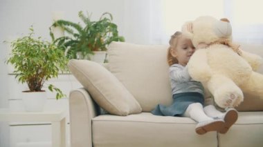 Küçük sarışın kızın oyuncak ayının arkasına saklanıp sessizlik işareti gösterdiği 4K video..