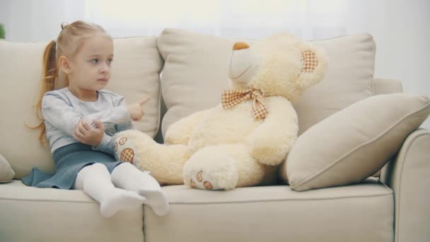 4k видео маленькой девочки, играющей с плюшевым медведем. — стоковое видео