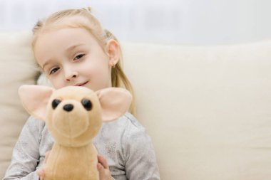 Küçük güzel kız eğlenceli bir oyuncağı kucaklıyor..