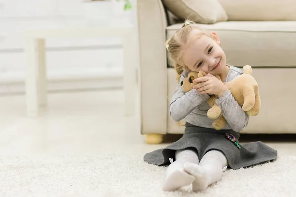 Foto gadis kecil duduk di lantai sambil memegang mainan. — Stok Foto