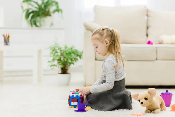 Bonito engraçado pré-escolar menina brincando com blocos de brinquedos de construção construir uma torre em um quarto ensolarado. — Fotografia de Stock