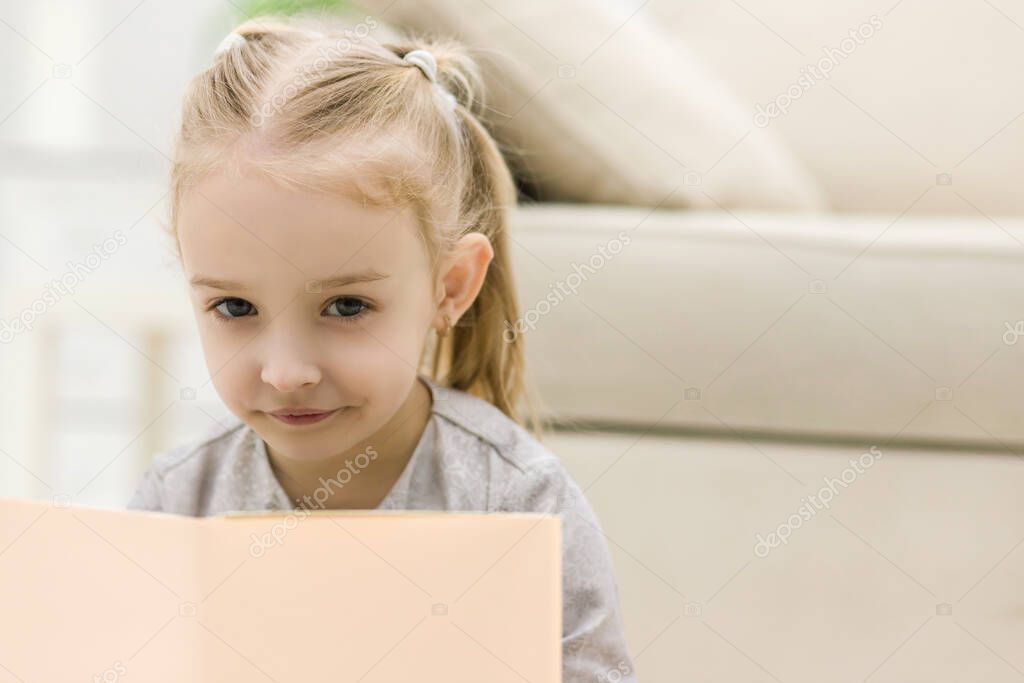 Sweet happy little girl reading a book.