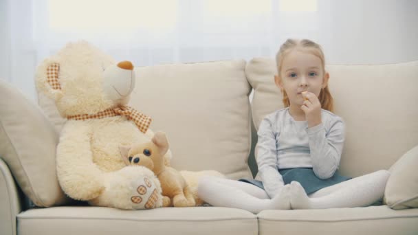 4k close up video de la pequeña hija rubia comiendo plátano y escuchando a alguien. — Vídeo de stock