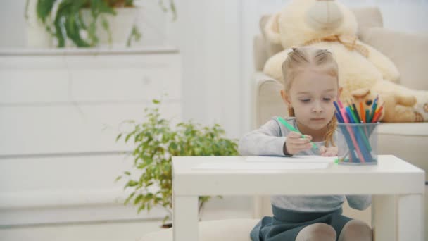 4k видео маленькая дочь с карандашами рисует что-то на столе дома. — стоковое видео