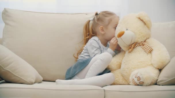 Oyuncak ayısıyla sırlarını paylaşan ve gülümseyen küçük tatlı bir kızın 4K videosu.. — Stok video