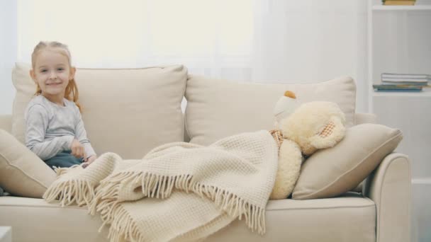 4k video of long-haired cute girl lying on sofa with teddy bear. — Stock Video