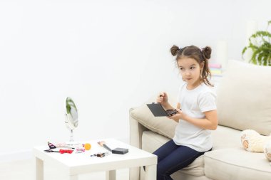 Makyaj yapmaya çalışan küçük esmer kızın fotoğrafı.,