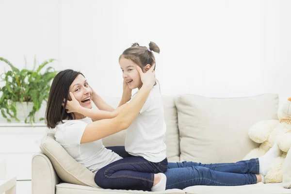 Foto de la madre jugando con su hija en el sofá. — Foto de Stock