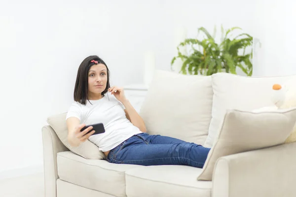 Foto einer lächelnden Frau, die auf dem Sofa liegt und Selfie macht. — Stockfoto