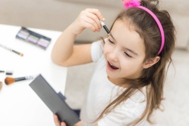 Aynaya bakan uzun saçlı küçük bir kızın portresi..