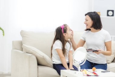 Oturma odasında annesiyle oynayan küçük kızın fotoğrafı..