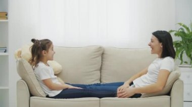 Oturma odasındaki beyaz kanepede yatan anne ve kızının 4k yavaş videosu..