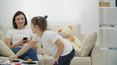 4k yavaş çekimde küçük bir kızın annesiyle kanepede otururken oynadığı video..