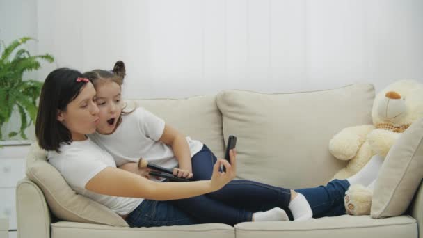 4k slowmotion video av mor och söt unge dotter med hjälp av smartphone och ta selfie. — Stockvideo