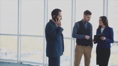 İş adamları arka plandaki bulanık ışık sorununu tartışıyorlar. Telefondaki adam ön cephede. Evet, tebrikler. Yumruklar yukarı. Uzayı kopyala Kapatın. 4K.